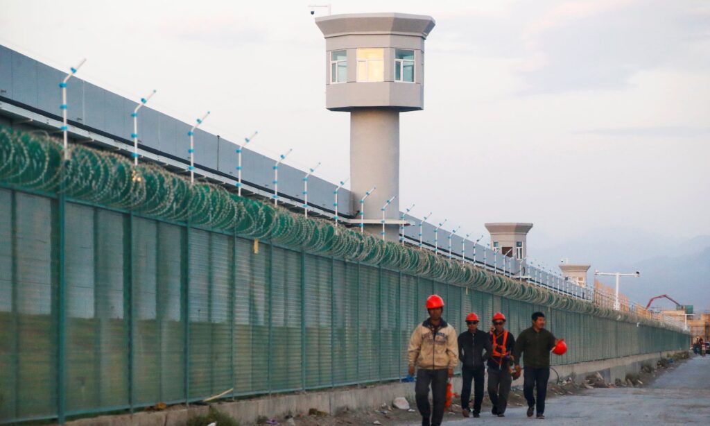 Workers at the perimeter fence of what is officially known as a vocational skills education centre in Xinjiang. Photograph: Thomas Peter/Reuters